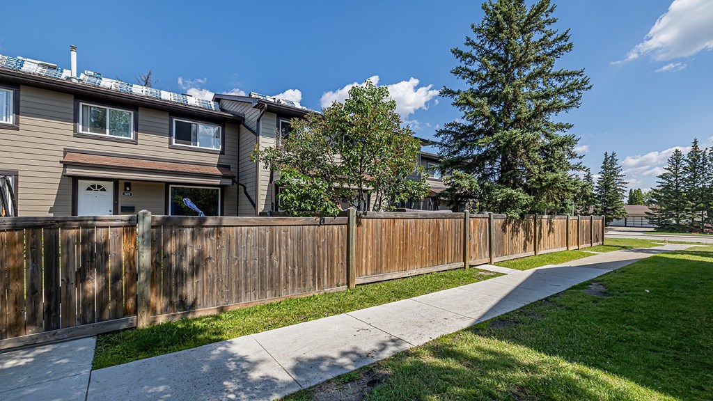 A row of houses with a sidewalk and a fence.