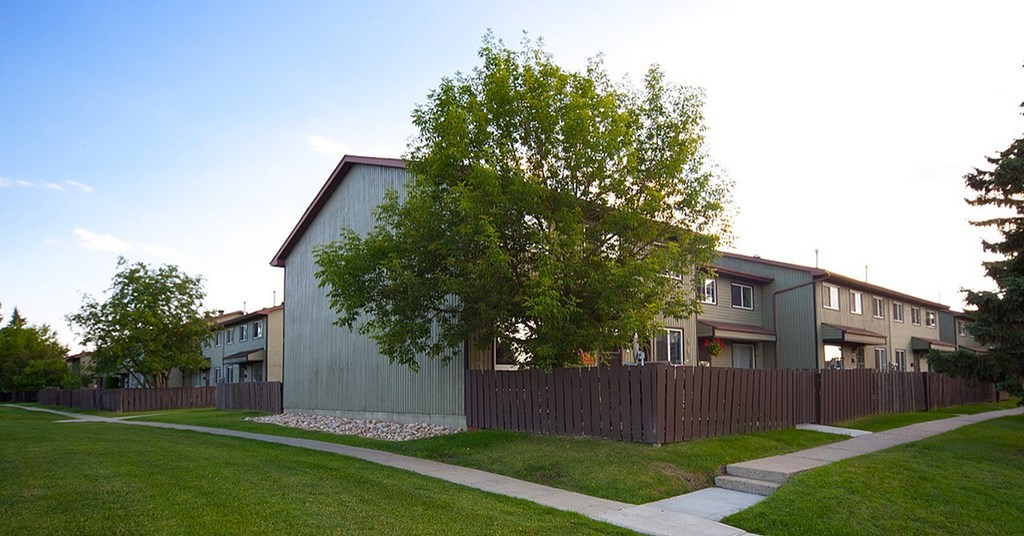 A tree in front of a building with a fence in front of it.