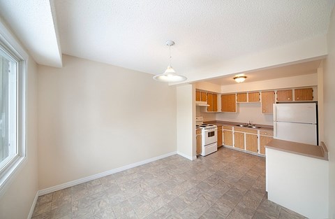 A kitchen with a refrigerator, sink, and cabinets.