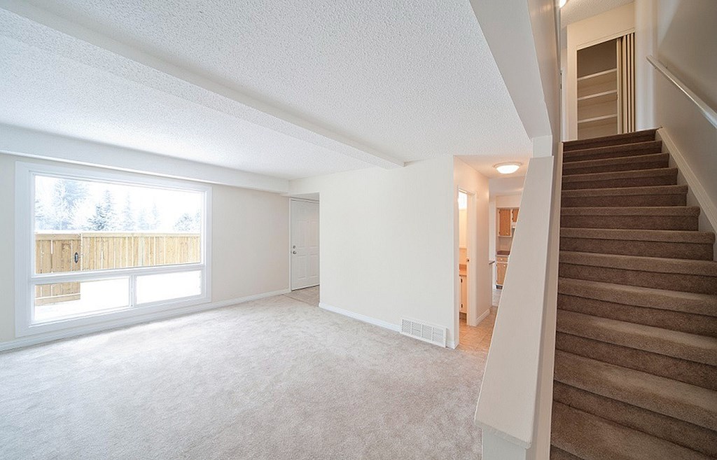 A spacious room with a staircase leading to another room.