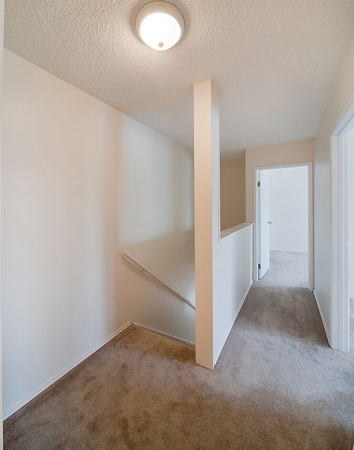 A hallway with a carpeted floor and a light on the ceiling.