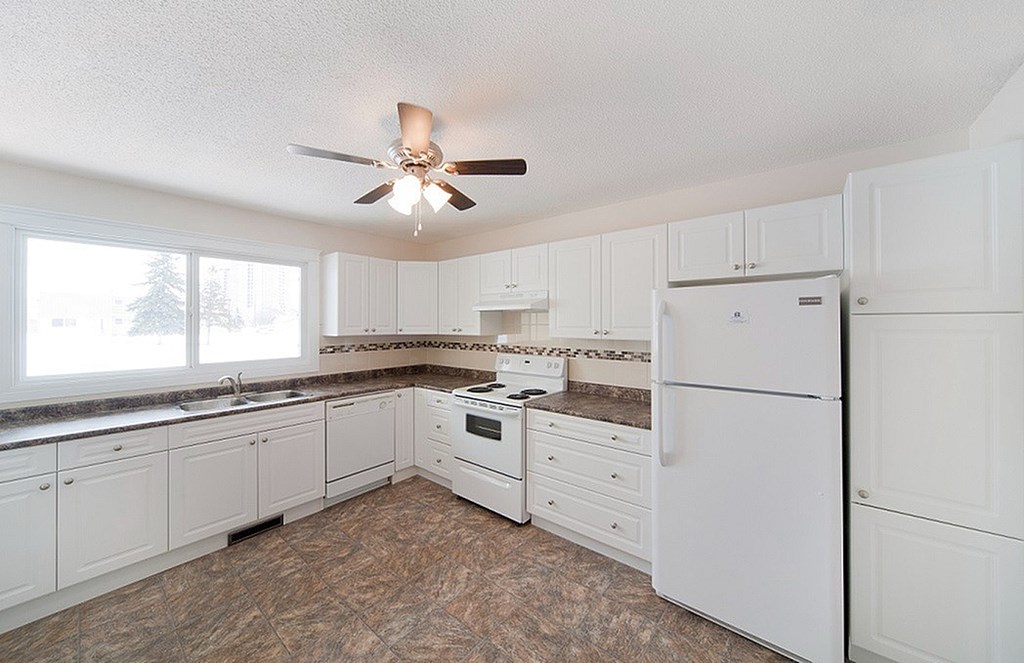 A kitchen with white appliances and cabinets.