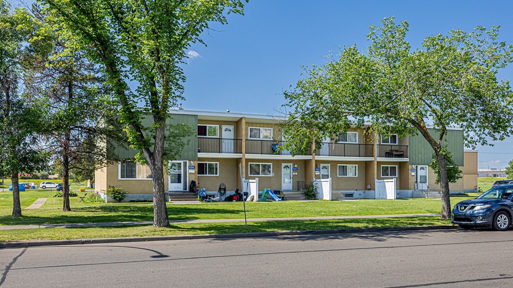 A tree in front of a building with a car parked in front of it.