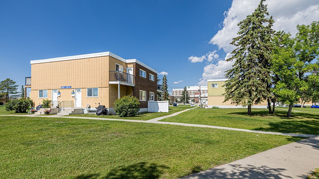 A modern building with a balcony and a small garden in front.