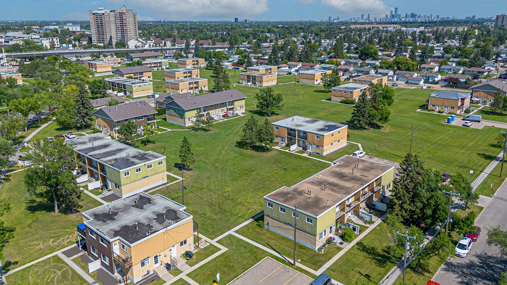 A large grassy area with several buildings in the background.