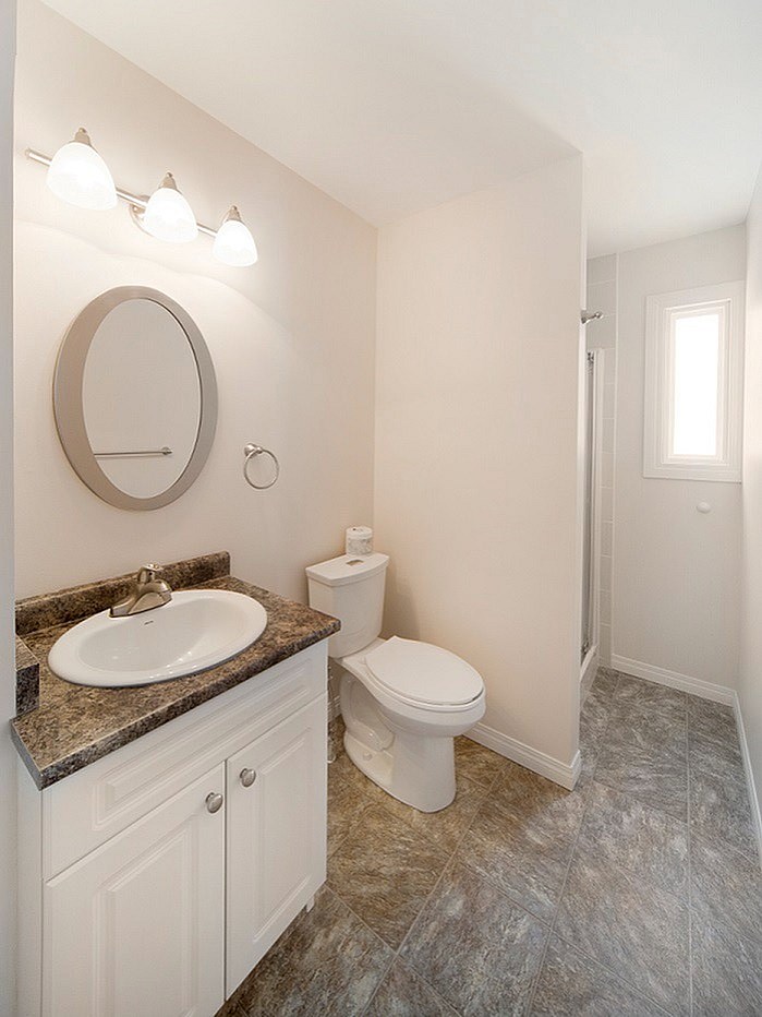 A bathroom with a toilet, sink, and mirror.
