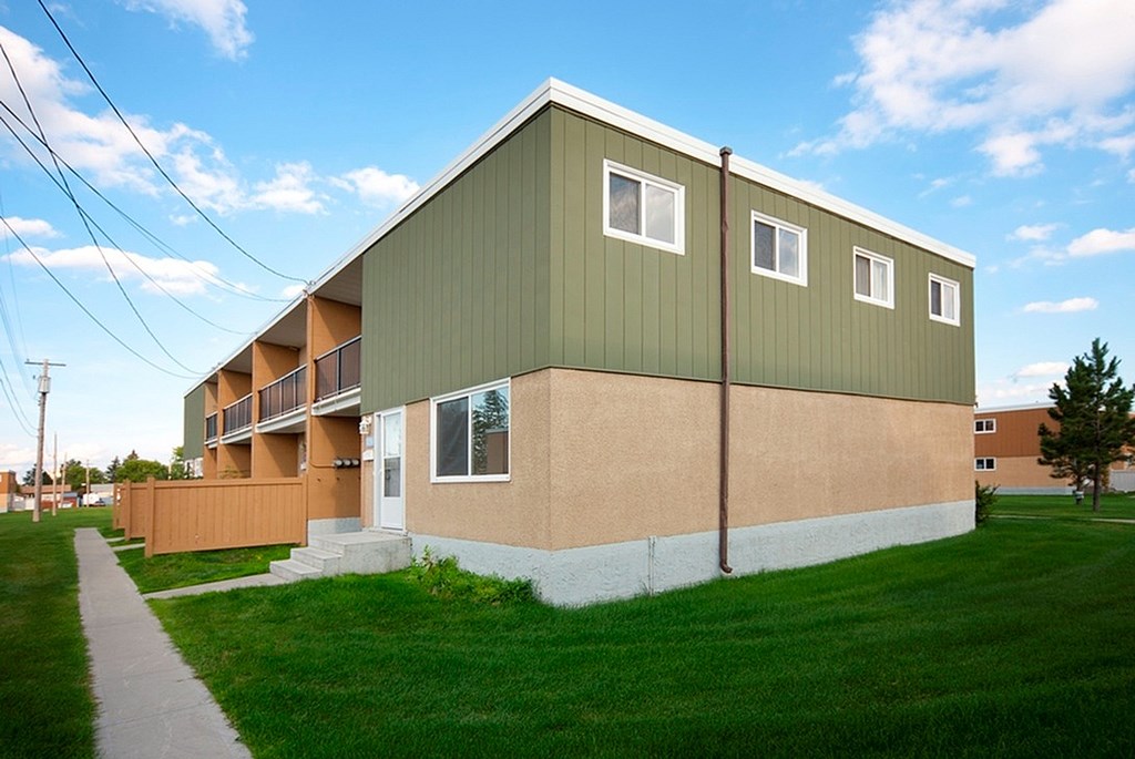 A green and beige building with a brown door and windows.