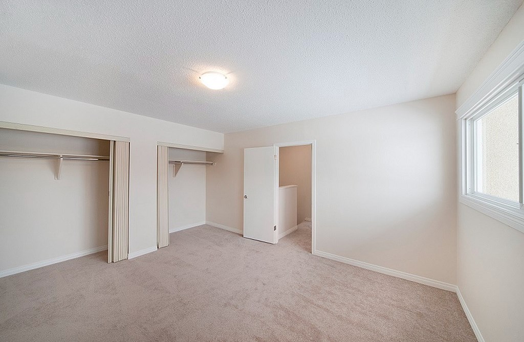 A room with a carpeted floor and a window on the right side.