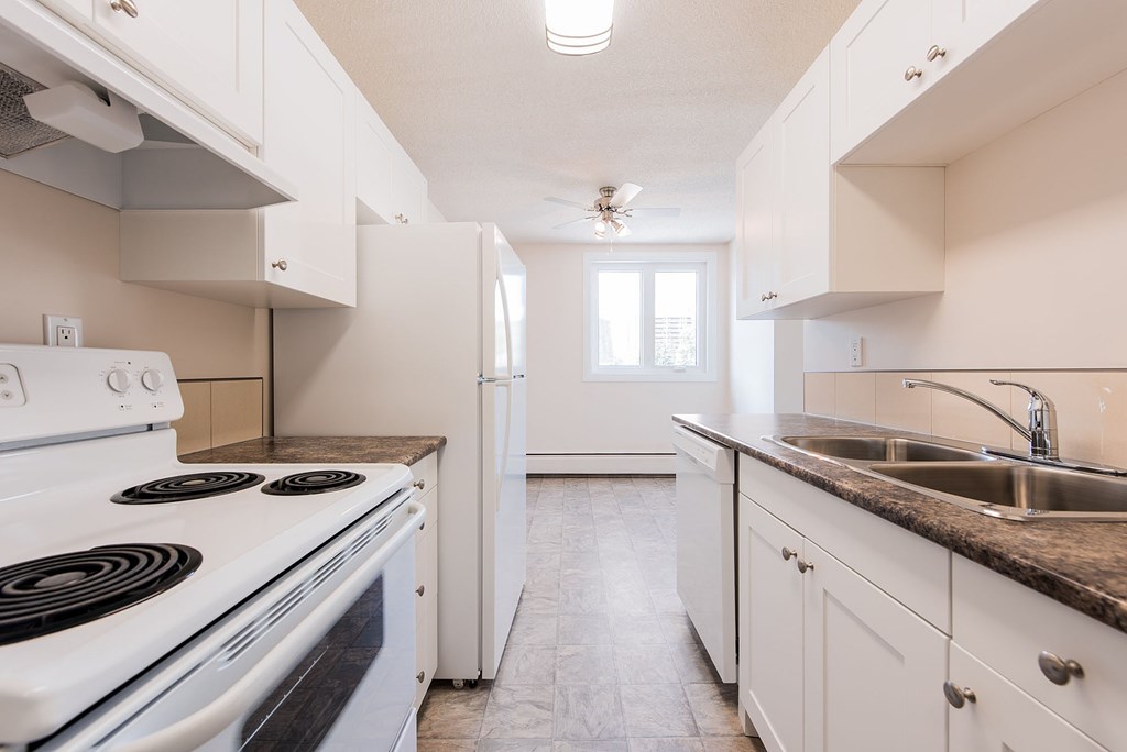 A white kitchen with a stove, sink, and refrigerator.