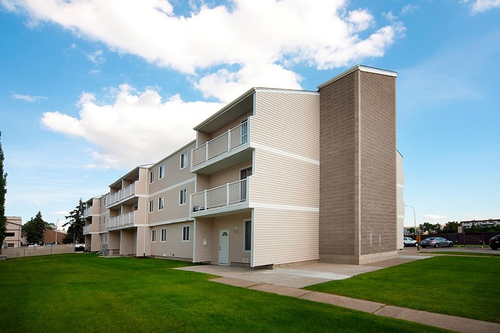 A modern apartment building with a grassy area in front.