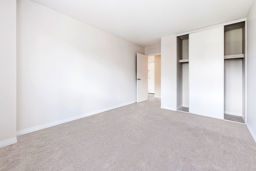 A spacious room with a carpeted floor and white walls.
