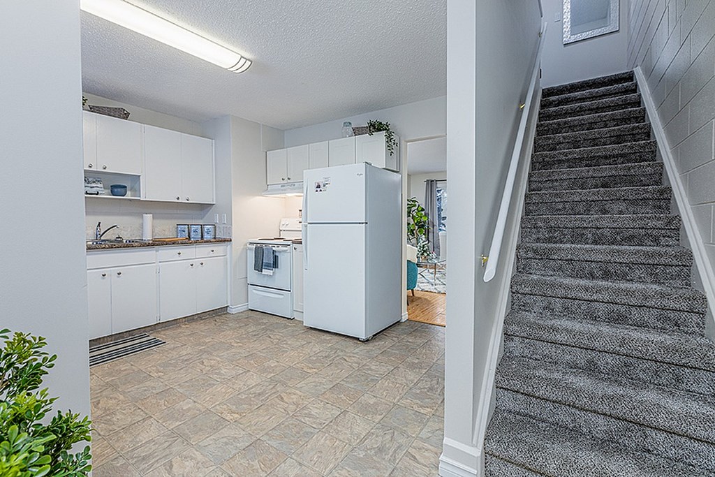 A kitchen with a staircase leading to the upper floor.