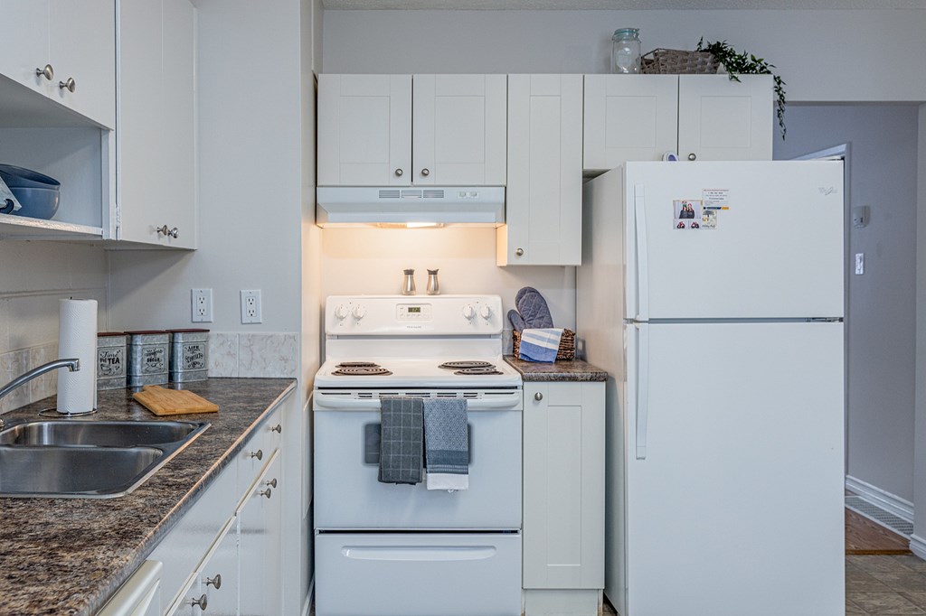 A white kitchen with a refrigerator on the right.