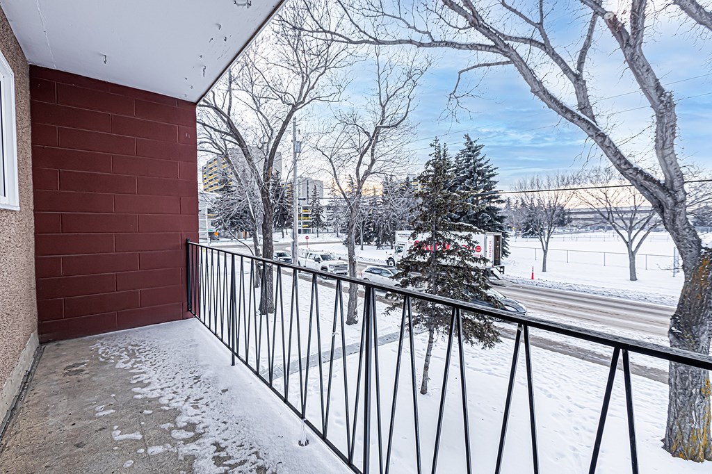 A balcony with a red wall and a metal railing.
