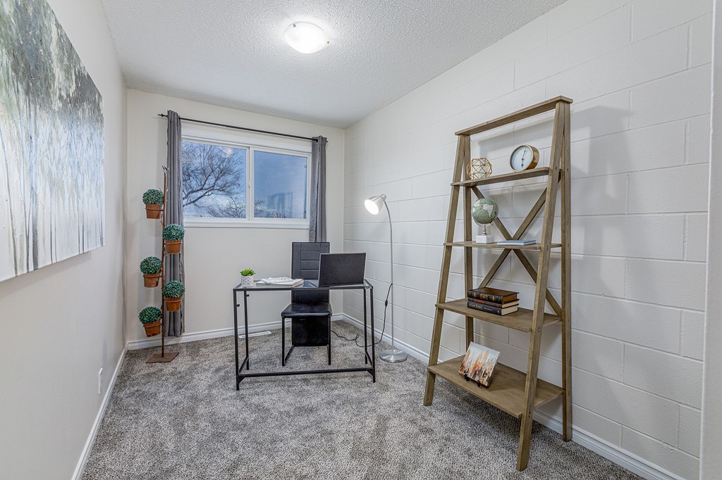 A room with a desk, chair, and a shelf with books and a clock.