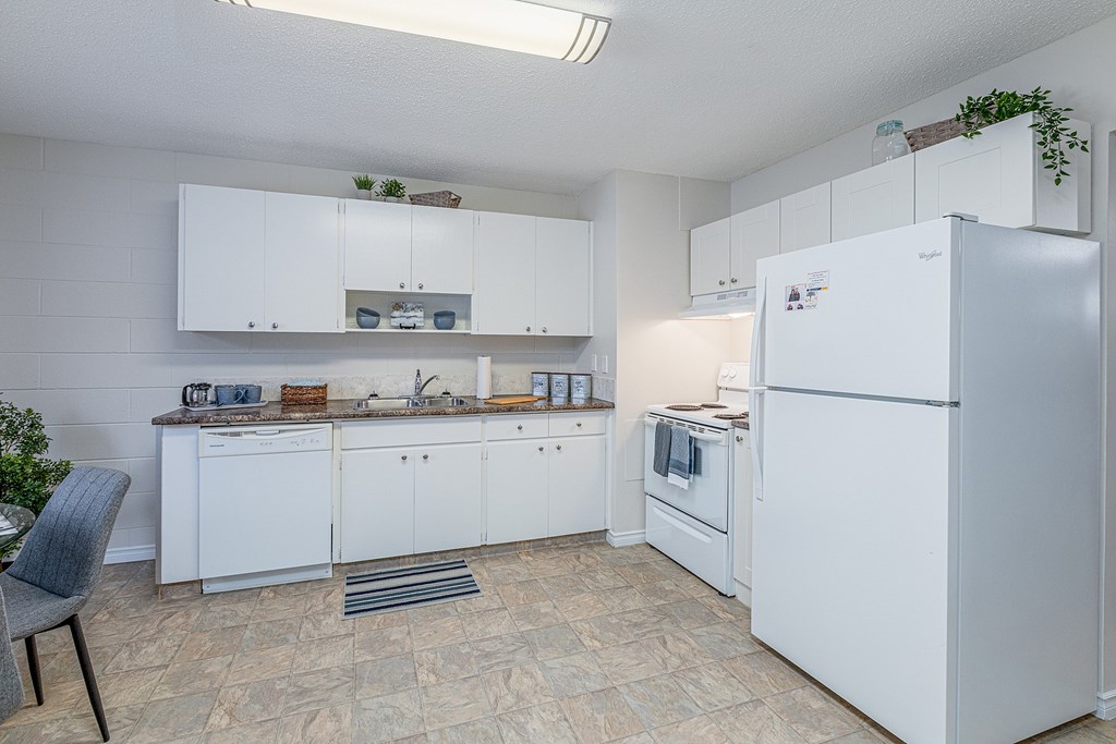 A kitchen with white cabinets and a refrigerator.