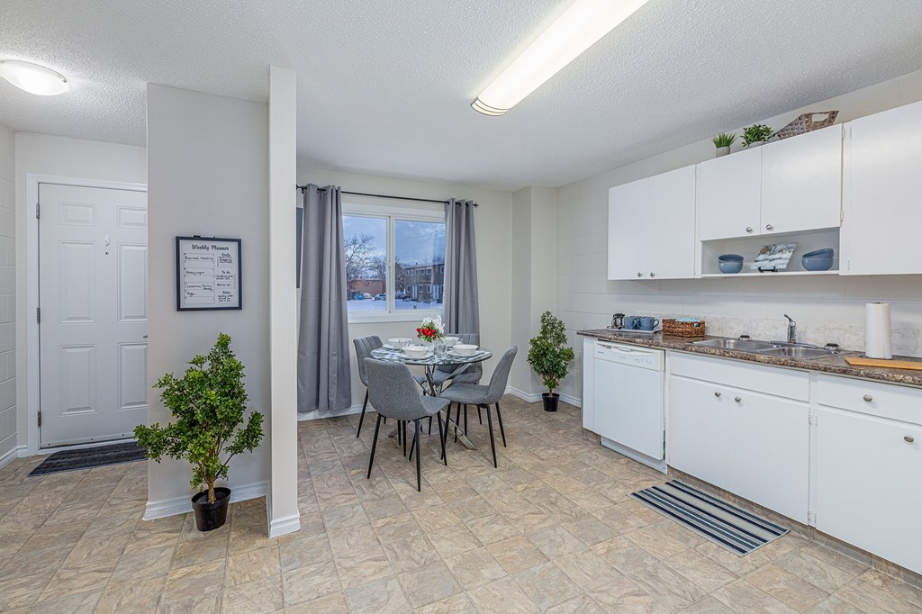 A kitchen with a table and chairs in front of a window.