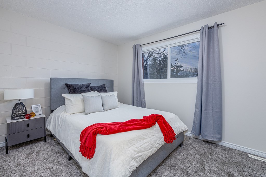 A bedroom with a large bed and a red blanket.