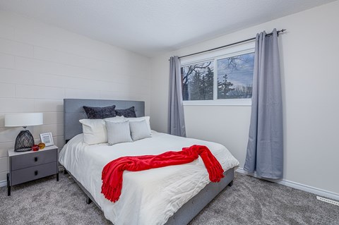 A bedroom with a large bed and a red blanket.