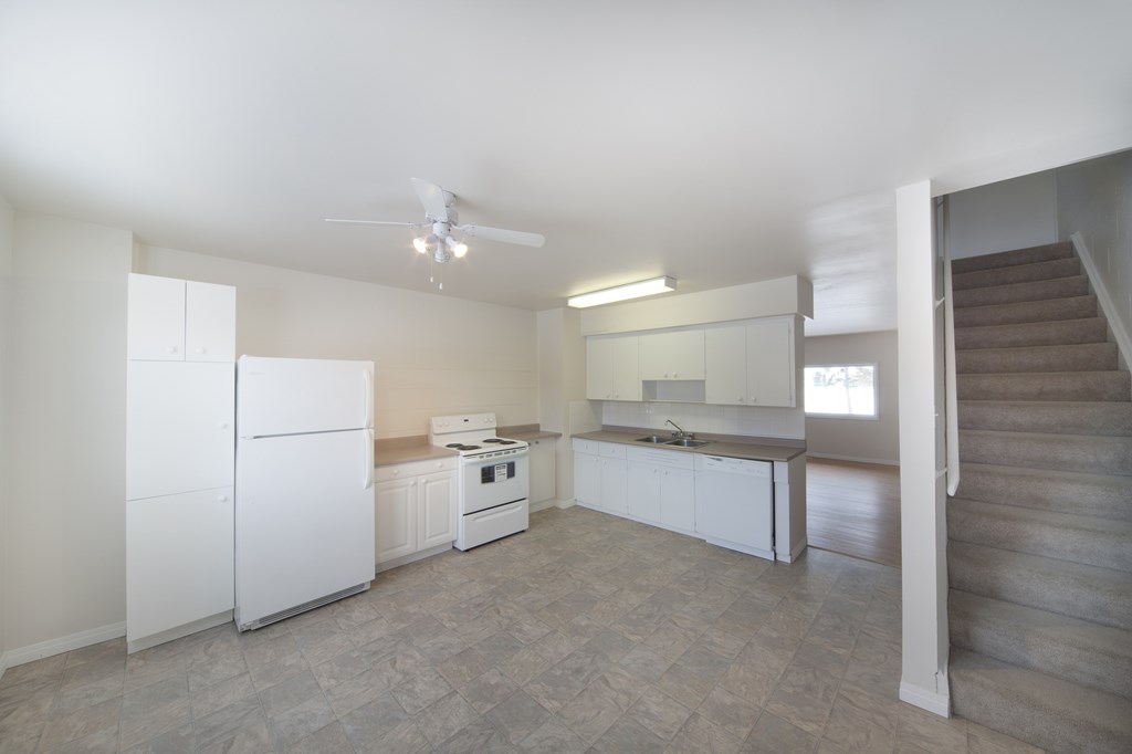 A white kitchen with a refrigerator, stove, and oven.