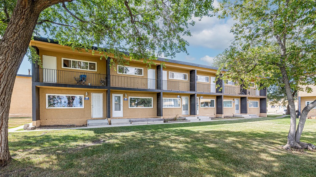 A building with a balcony and a tree in front of it.