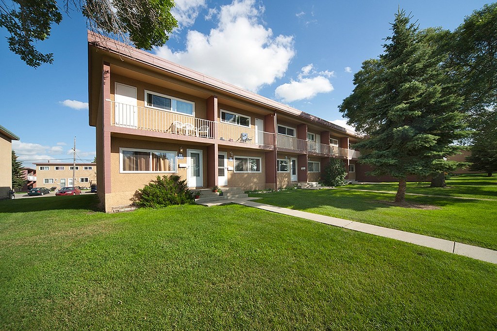 A large apartment building with a green lawn in front.