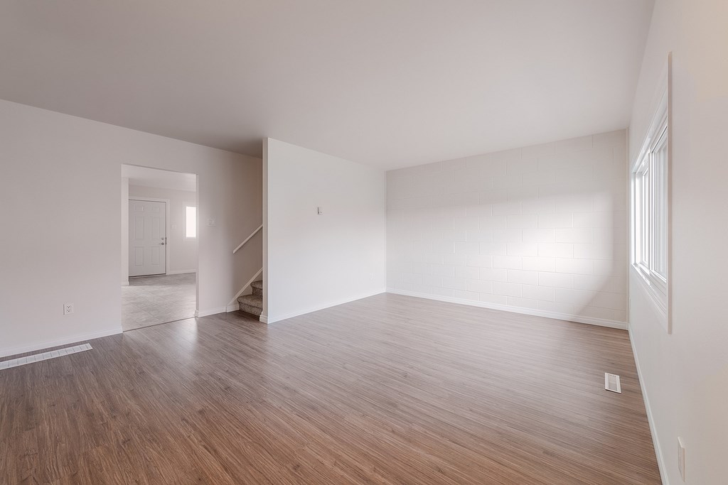 A room with wooden flooring and white walls.