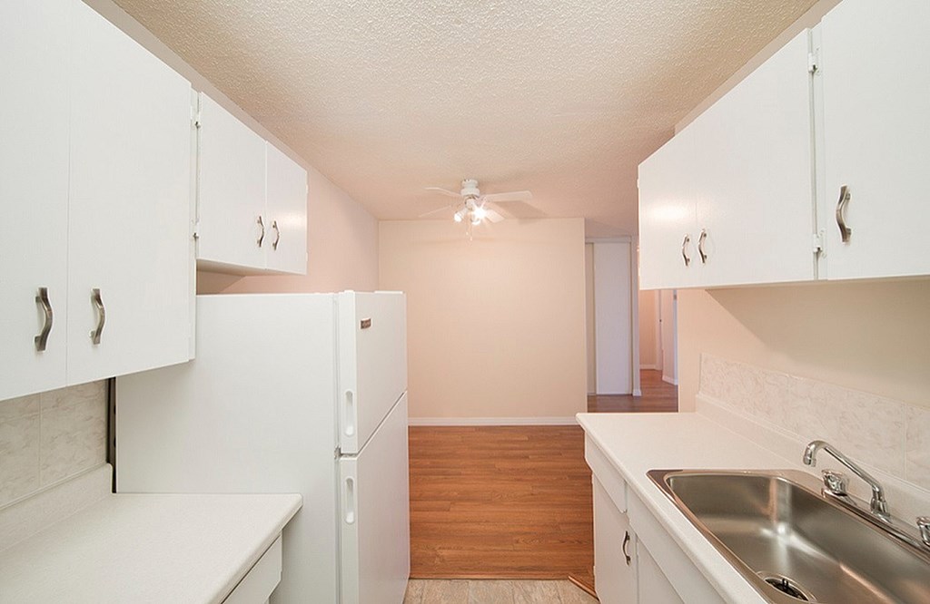 A kitchen with white cabinets and a white counter top.