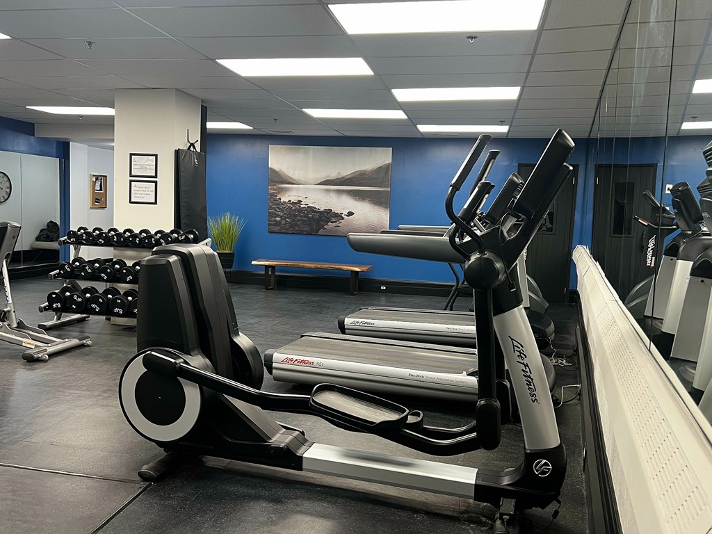A gym with a rowing machine in the foreground.