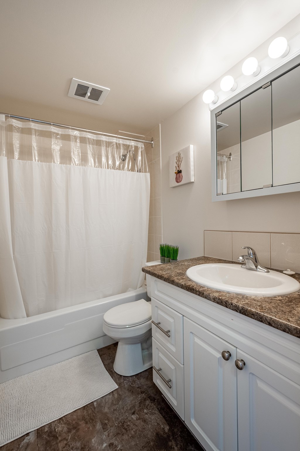 A bathroom with a toilet, sink, and mirror.