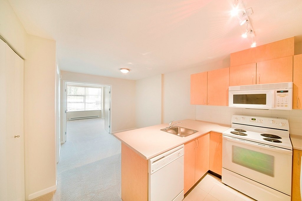 A kitchen with white appliances and orange cabinets.
