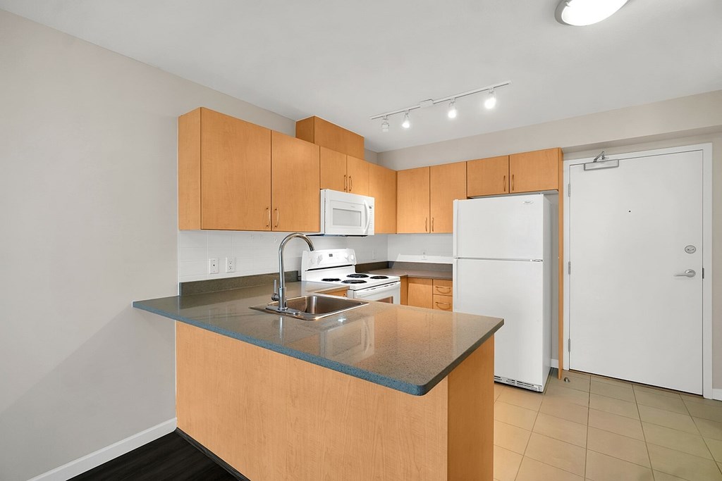 A kitchen with a white refrigerator and wooden cabinets.