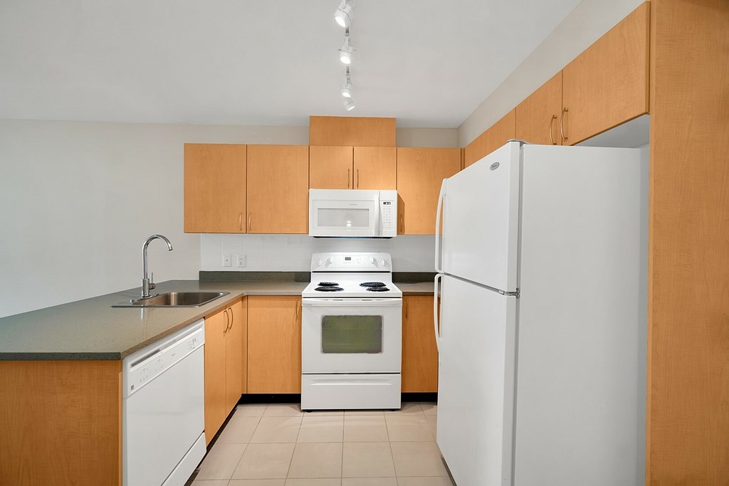 A kitchen with white appliances and wooden cabinets.