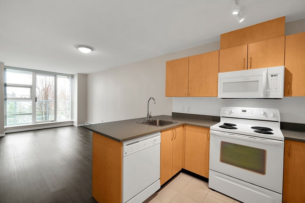 A kitchen with white appliances and wooden cabinets.