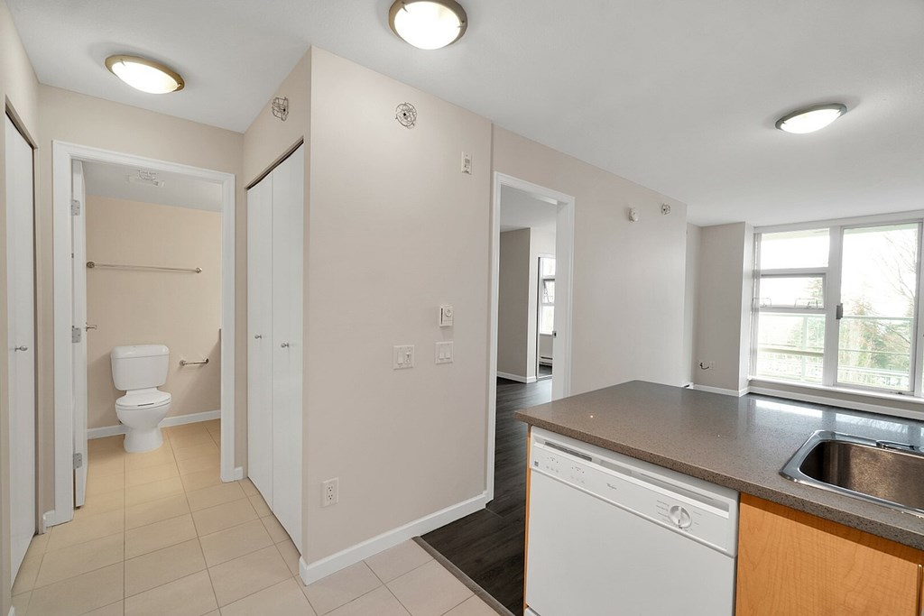 A small, clean, and well-lit bathroom with a toilet, sink, and a window.