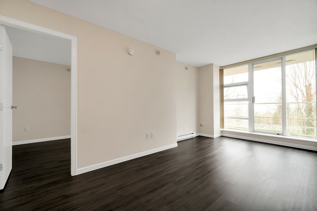 A room with a white door and a window with a view of trees outside.