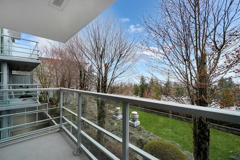 A balcony with a metal railing overlooks a tree and a building.