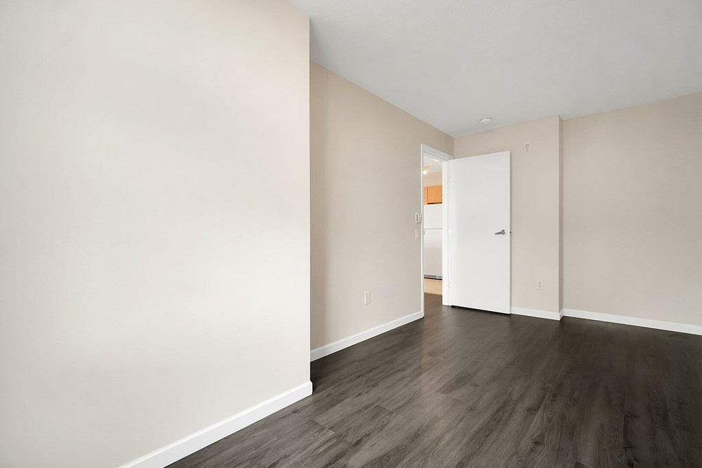 A room with a white door and wooden flooring.