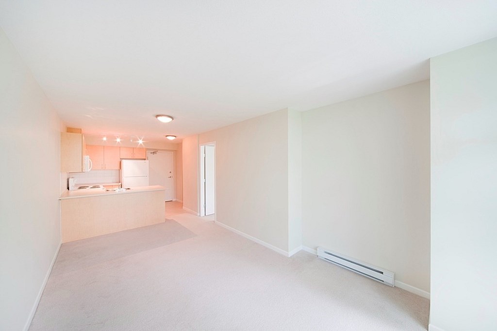 A white room with a window and a radiator on the wall.