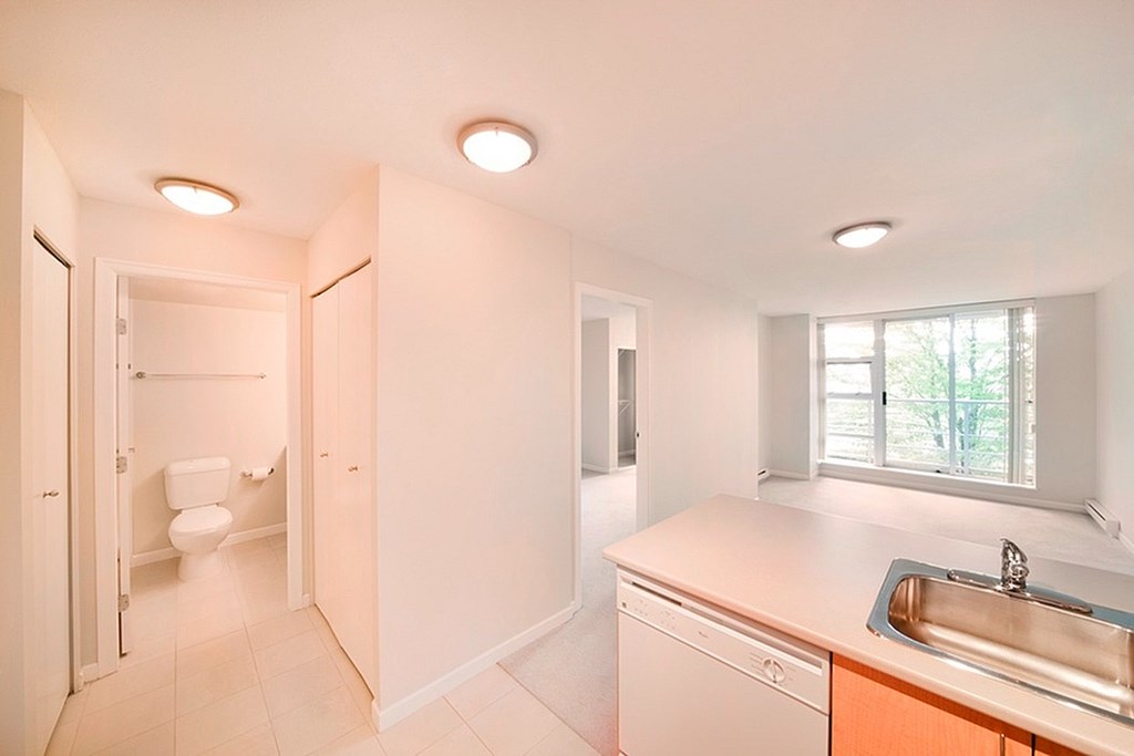 A bathroom with a toilet, sink, and window.