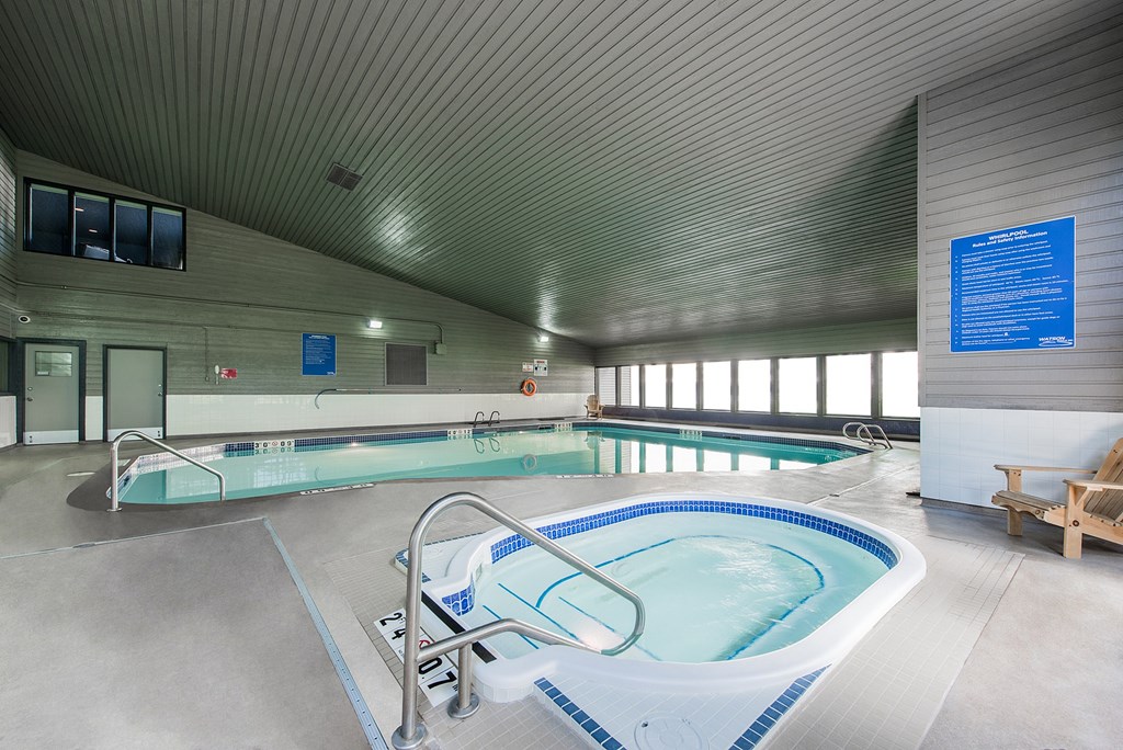 A large indoor swimming pool with a blue tiled edge and a metal ladder.