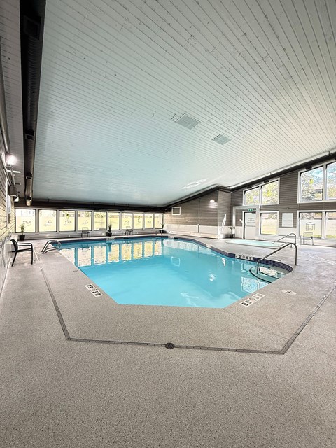 A large indoor swimming pool with a blue tiled edge and a metal ladder.
