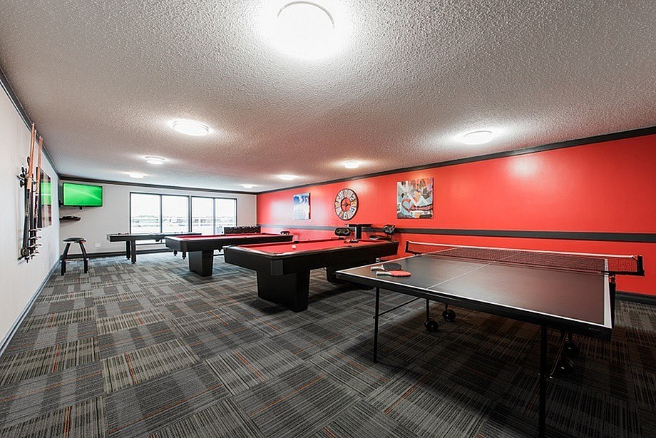 A ping pong table is in the middle of a room with a carpeted floor.