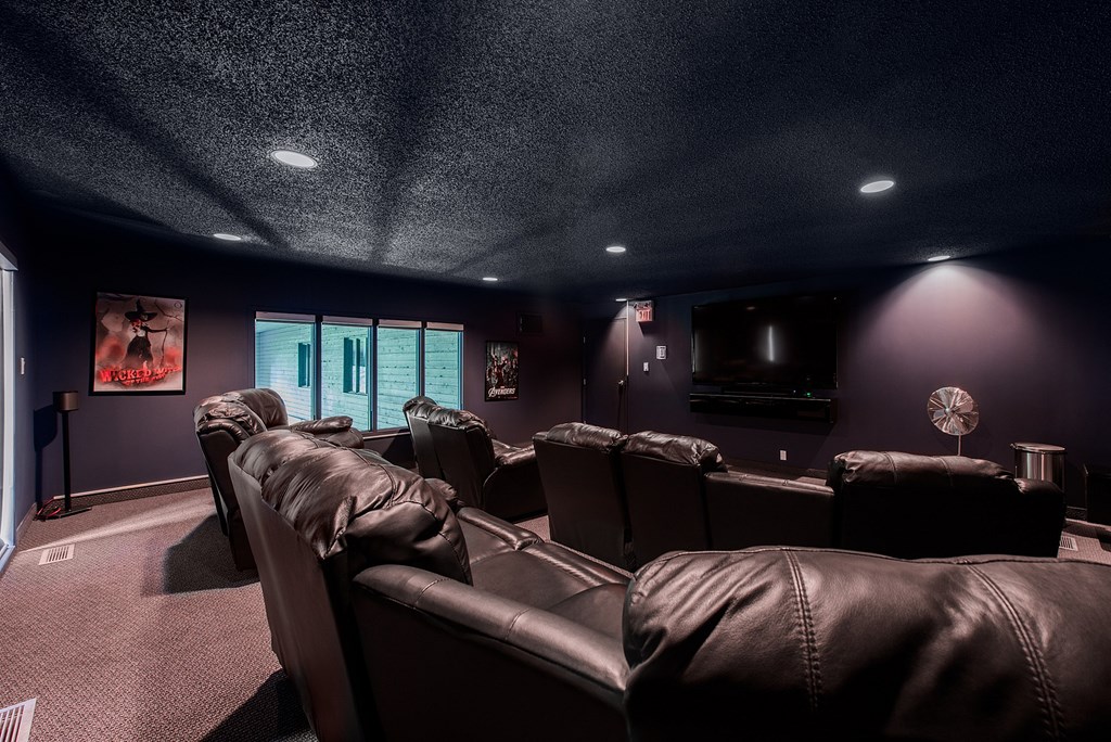 A dark room with a row of leather chairs facing a screen.