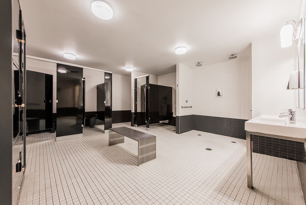 A bathroom with a white tiled floor and black and white tiled walls.