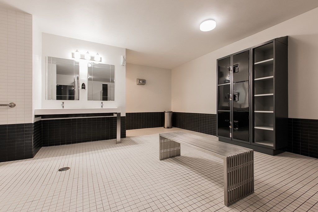A bathroom with a black and white tiled floor and a large mirror above a vanity.