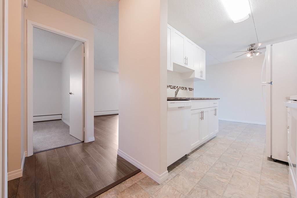 A kitchen with white cabinets and a wooden floor.