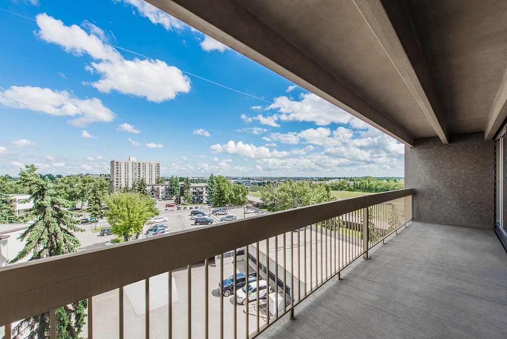 A balcony overlooks a parking lot and buildings.