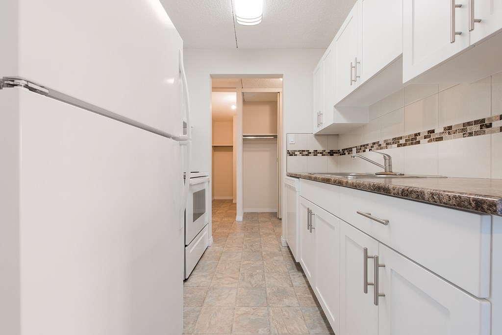 A kitchen with white cabinets and a marble countertop.