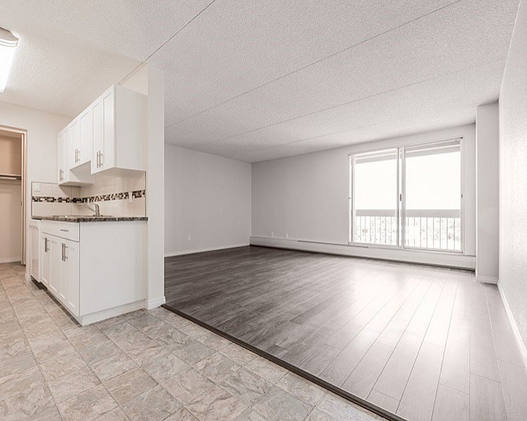 A spacious room with a kitchen area and a large window.